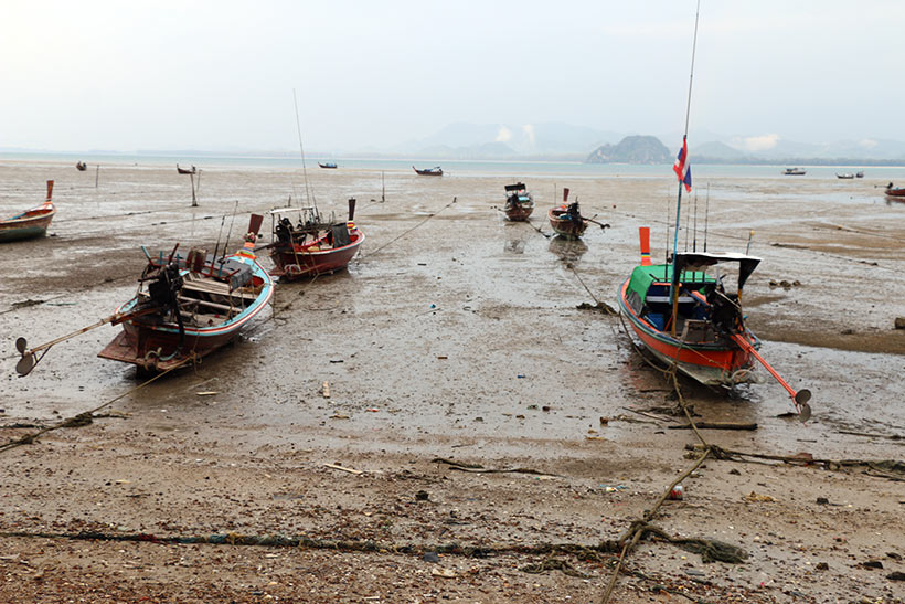 Barcos atolados com a maré baixa no cais do vilarejo de Koh Mook