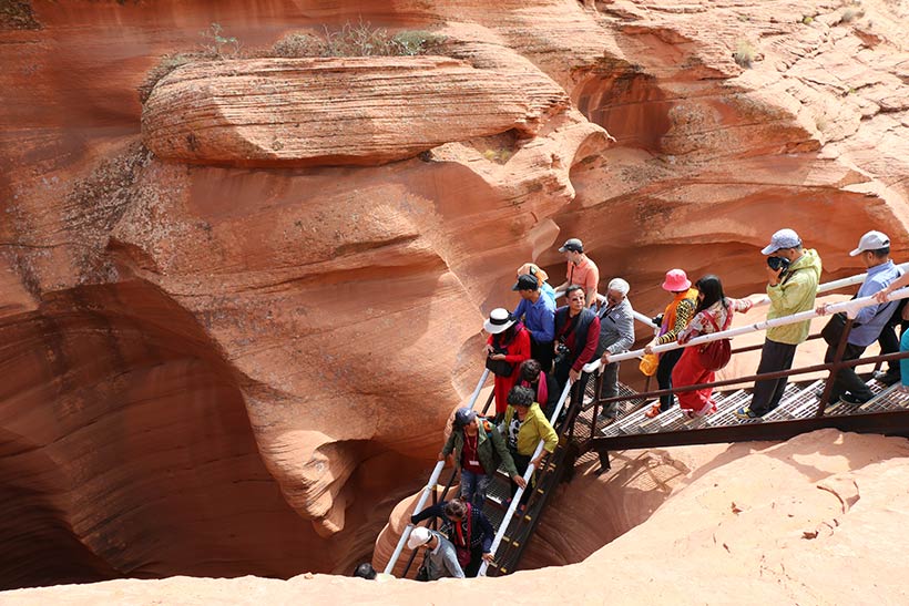 Fila de turistas descendo as escadas para o interior do Lower Antelope Canyon